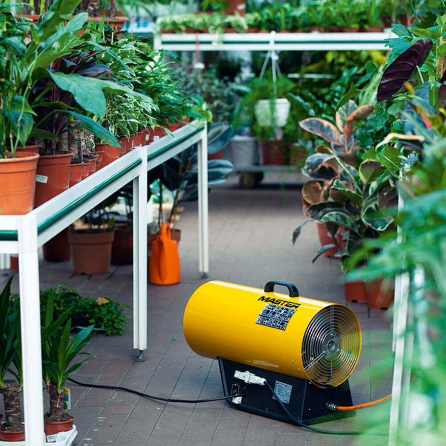 an image of an electric heater inside a greenhouse filled with plants